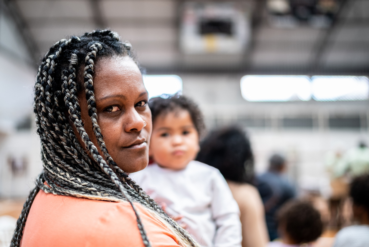 Portrait of a mature woman carrying her son waiting in line at a community center
